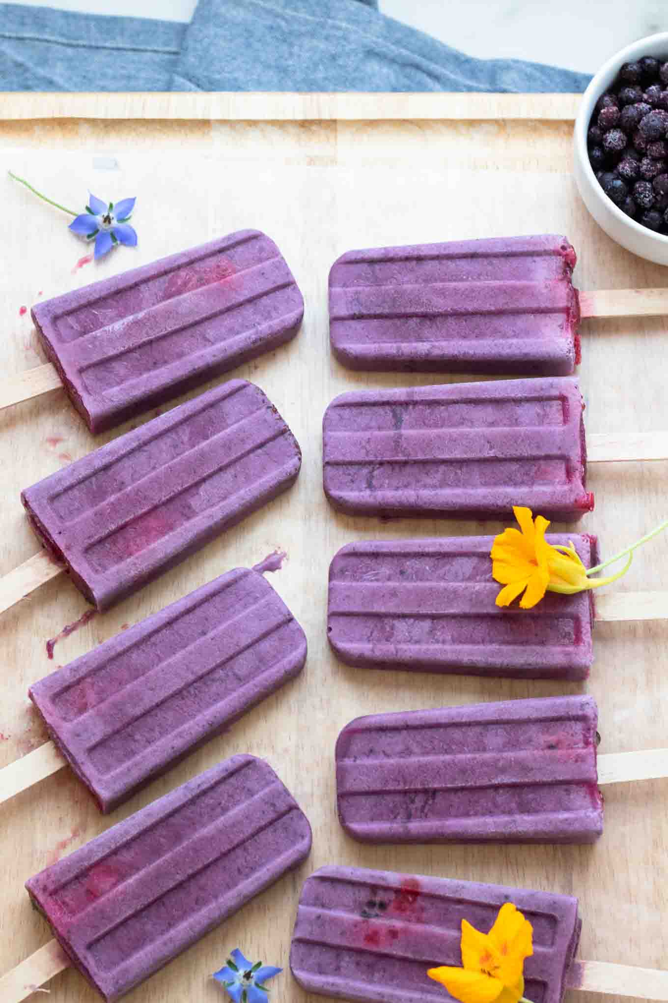 Vegan Blueberry Yogurt Popsicles lined up on a cutting board.