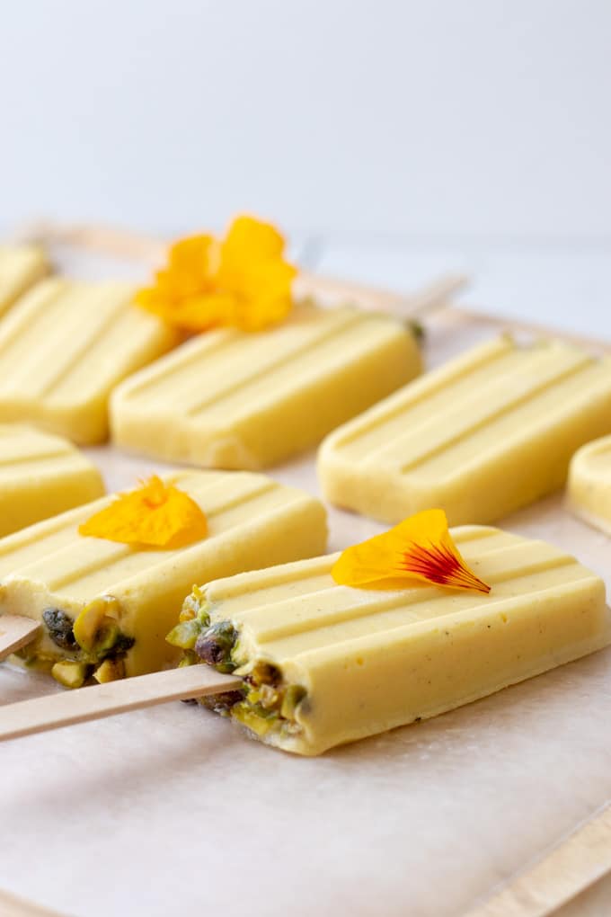 yellow mango coconut popsicles lying on wax paper.
