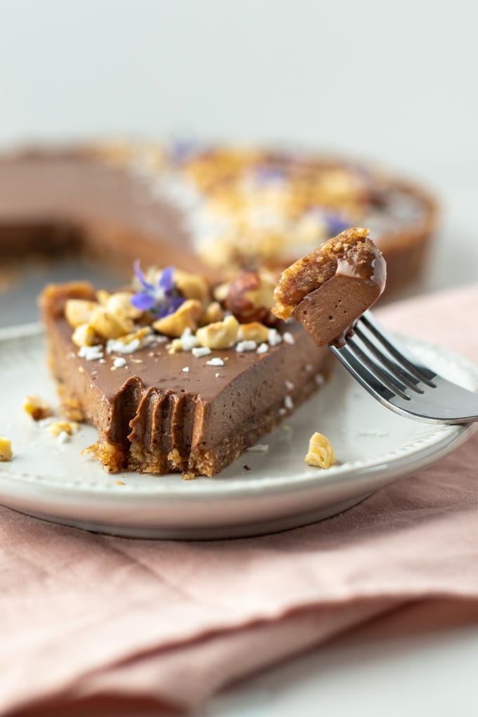 close-up shot of a bite of a piece of chocolate tart on a fork. 