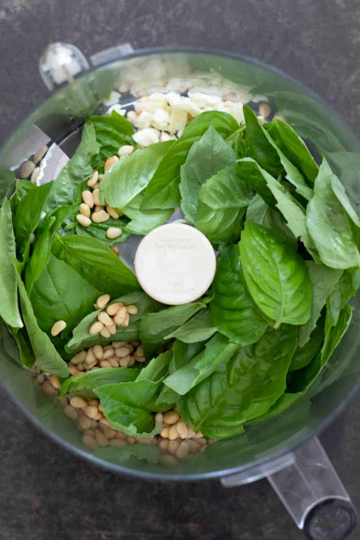 pesto ingredients inside the bowl of a food processor.