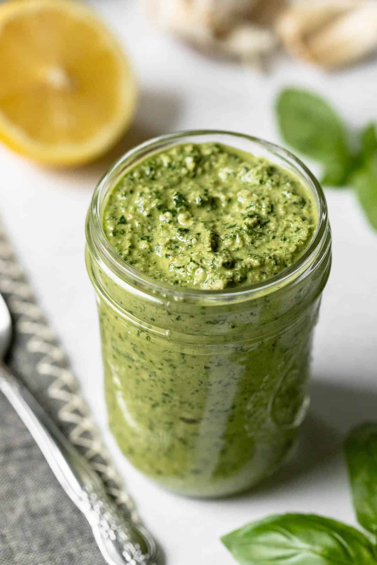 creamy vegan pesto in a small glass jar showing chunky texture.