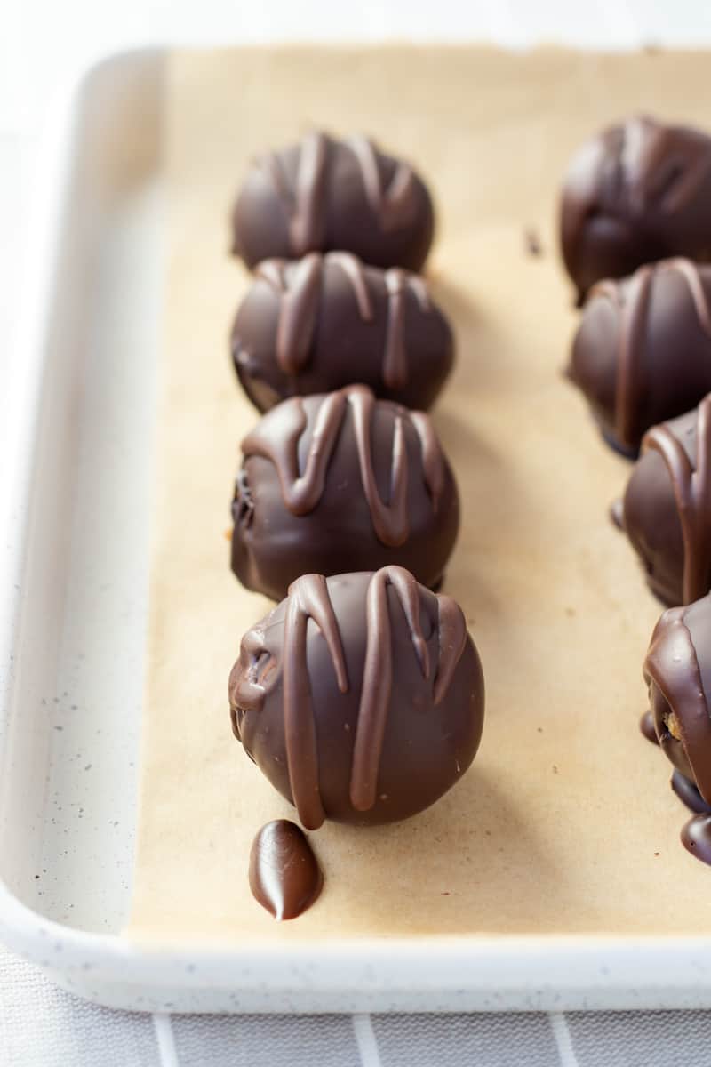 cookie dough bites coated in dark chocolate on a parchment lined baking sheet