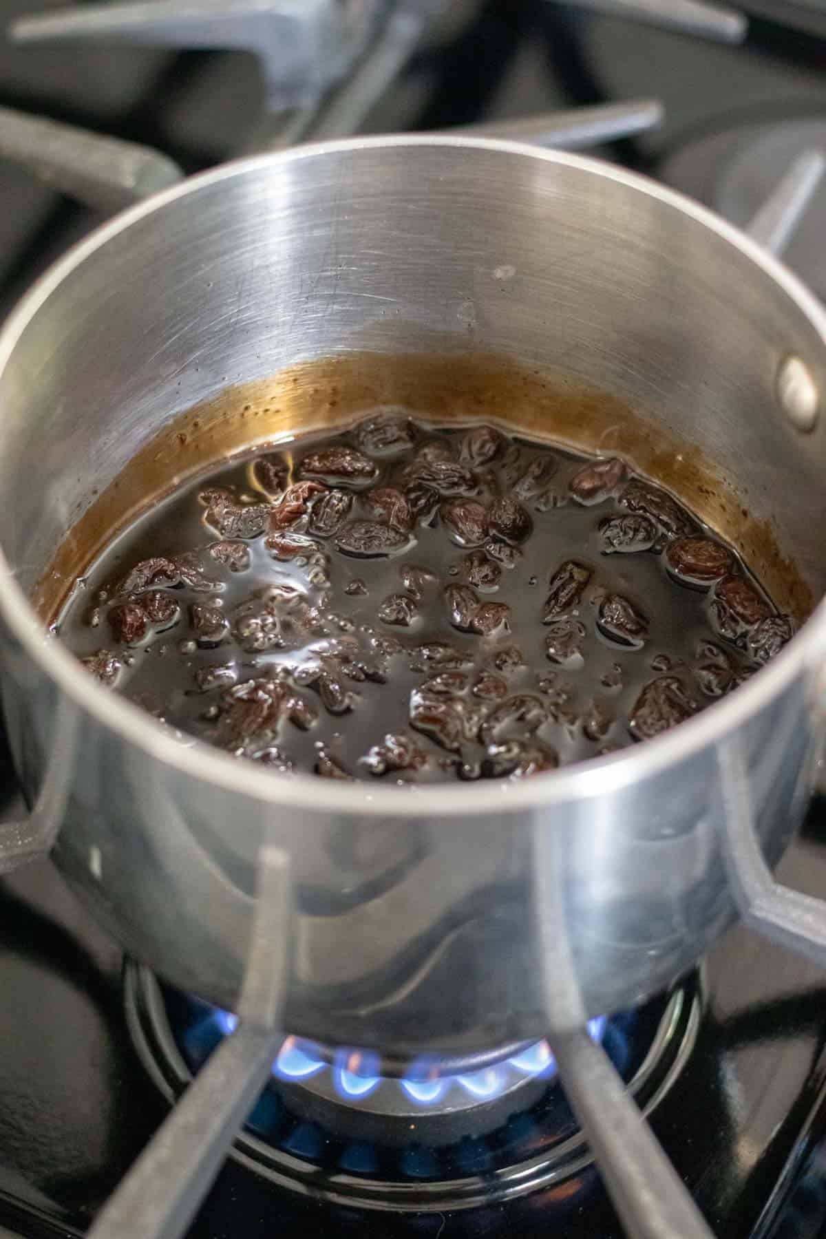 raisins and balsamic vinegar reducing in a sauce pan on the stove.