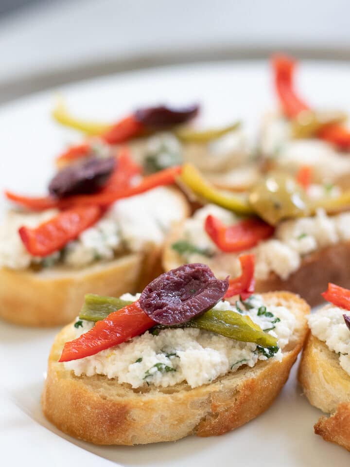 Vegan Crostini with herbed almond ricotta on a white plate