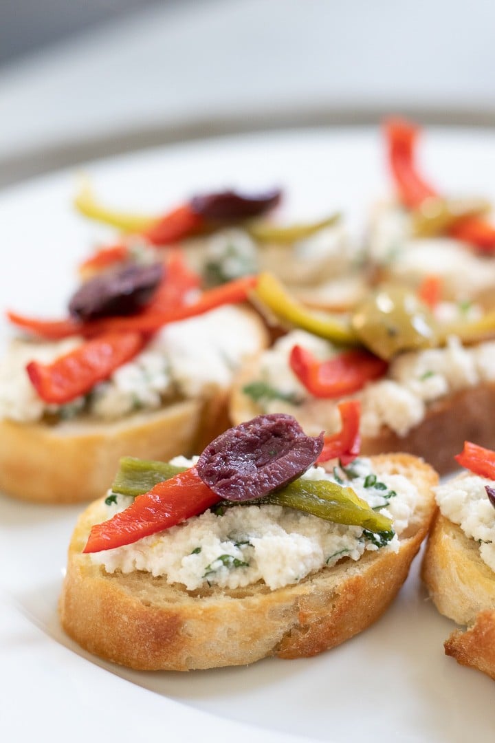 Vegan Crostini with herbed almond ricotta on a white plate