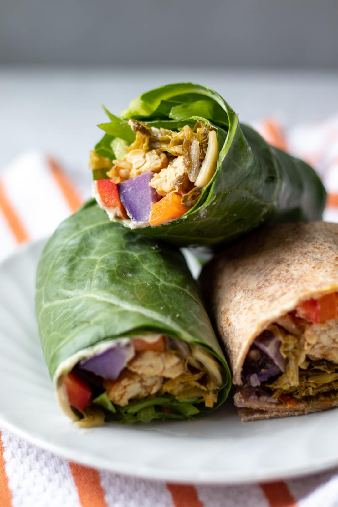 Three Kimch Tempeh Wraps stacked on a plate.