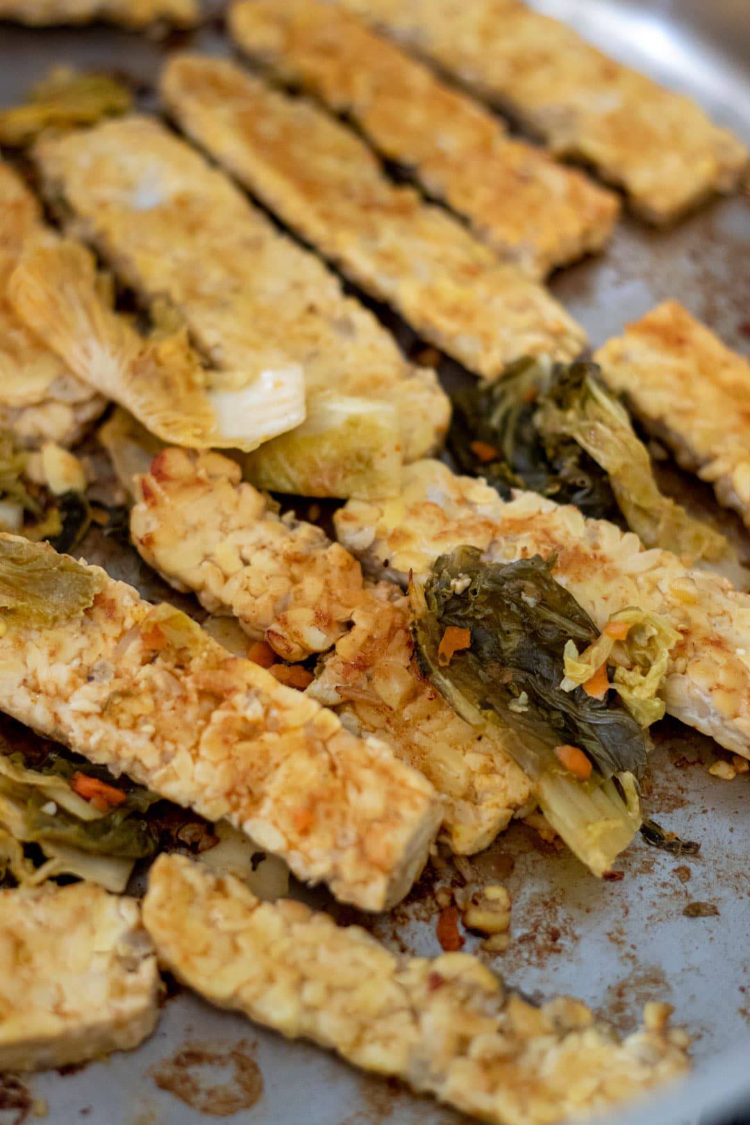 Sauteing marinated tempeh in a pan.