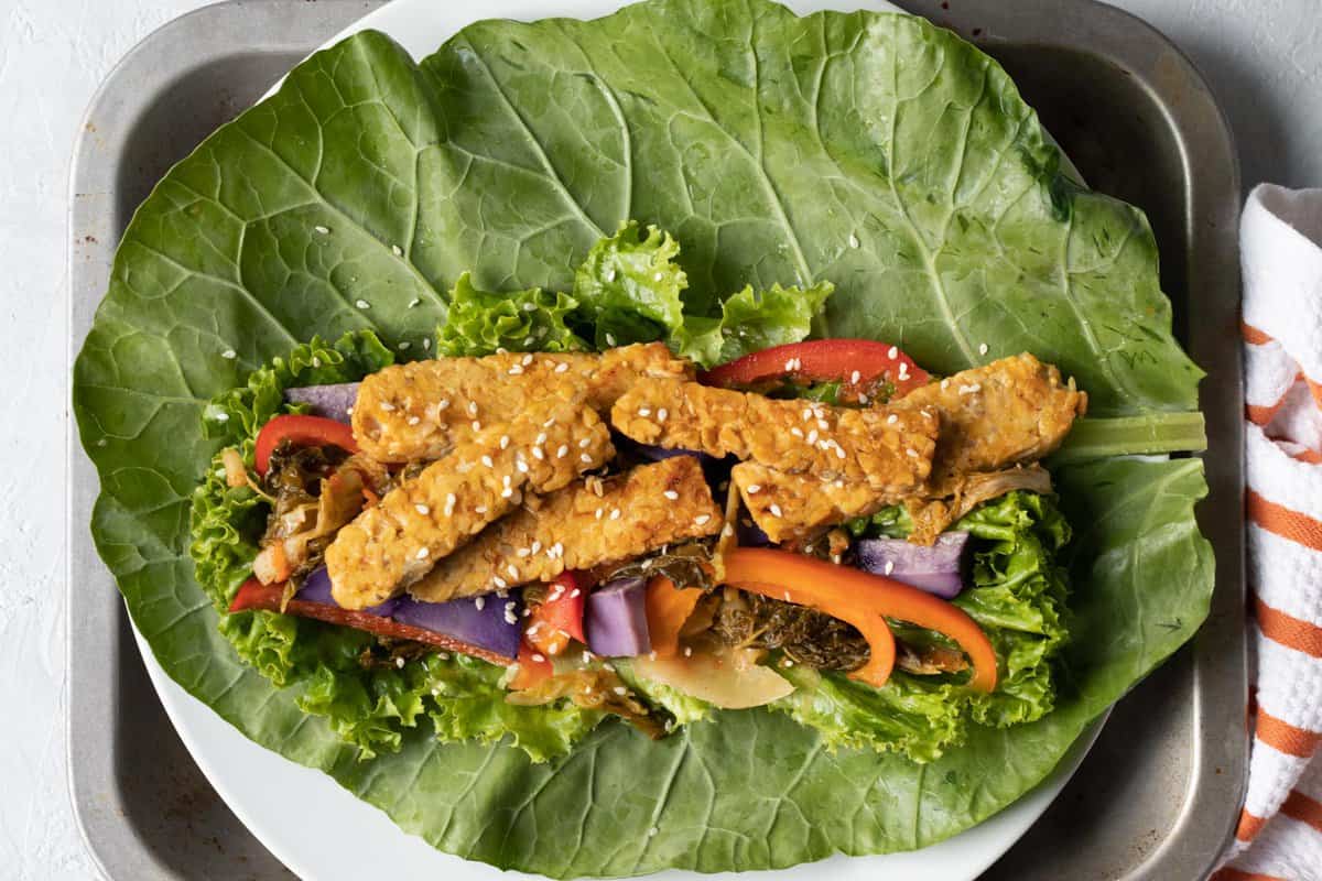 large collard leaf with tempeh and vegetable filling spread on top.