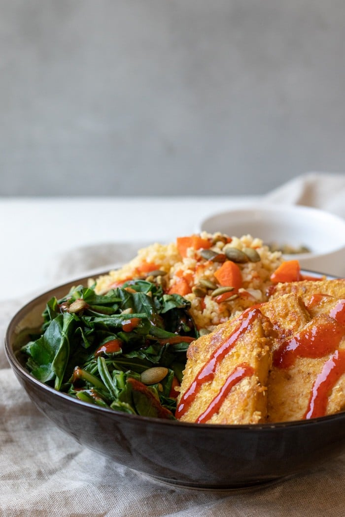 baked sweet mustard tofu, collard greens, and millet pilaf in a bowl