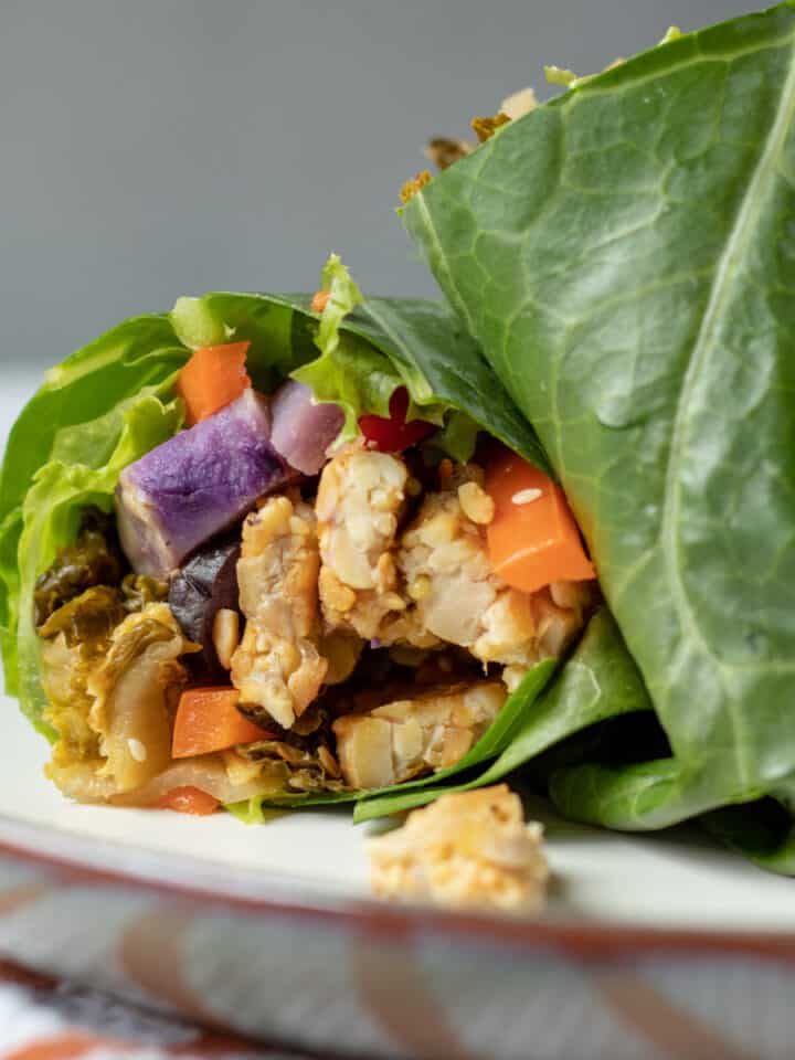 close up of a cut collard wrap showing tempeh and vegetables inside.