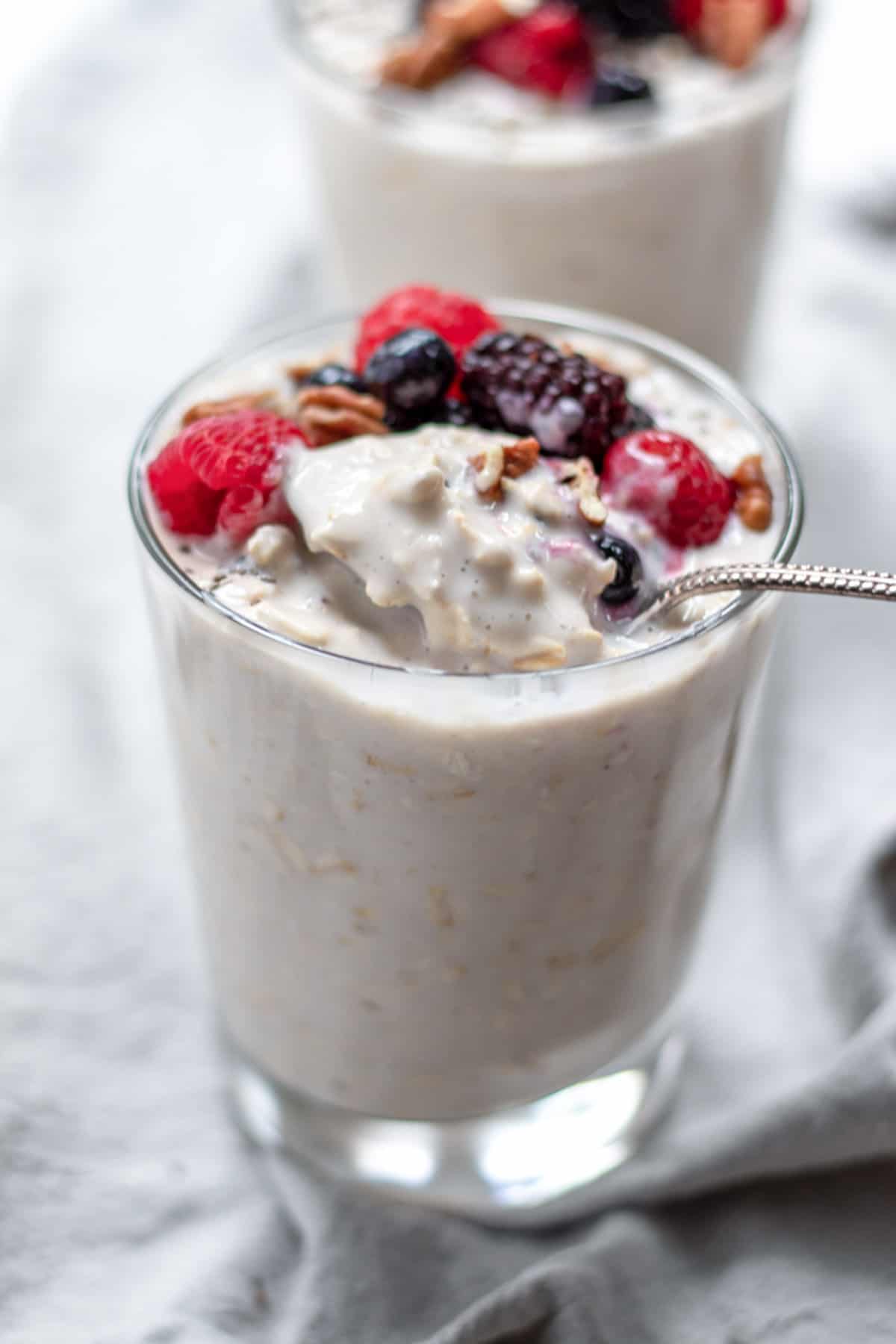 Spooning up oats and yogurt from a small glass.