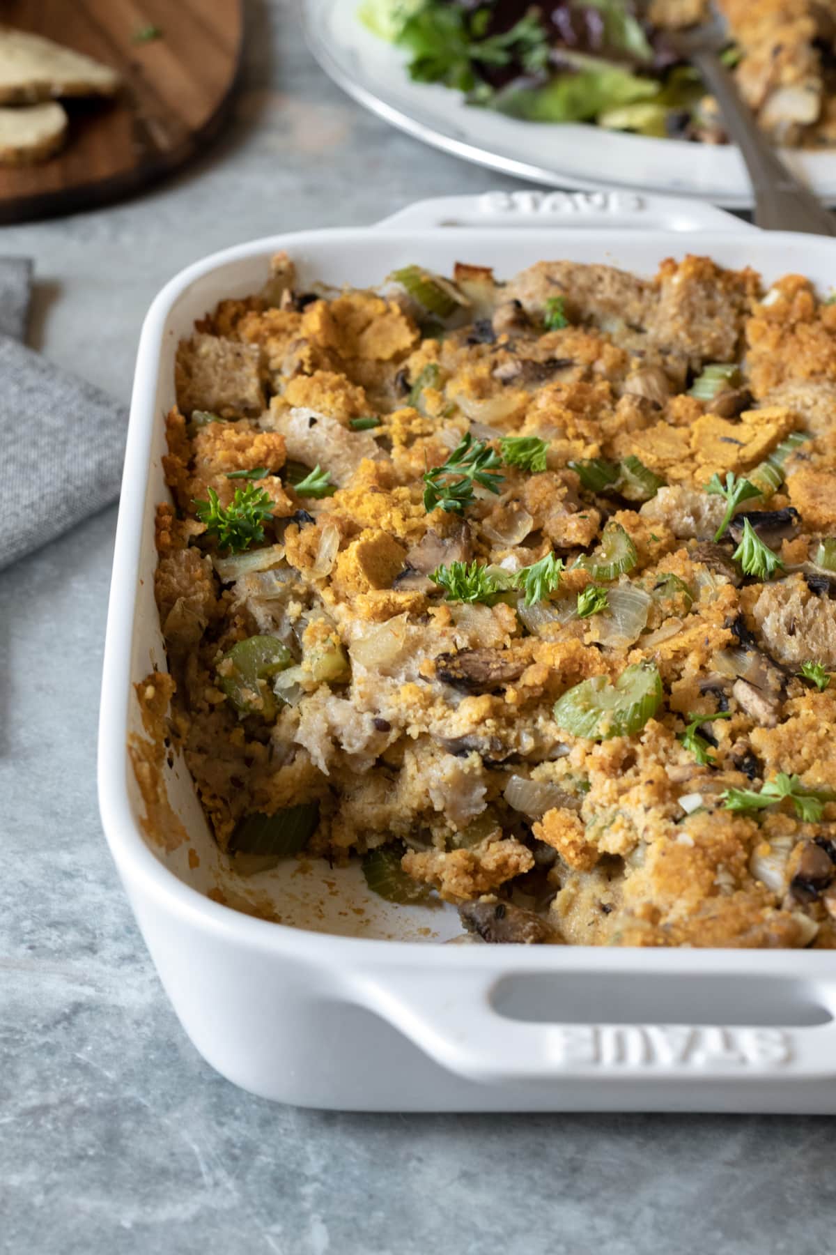 baked cornbread dressing with other vegan Thanksgiving foods in background.