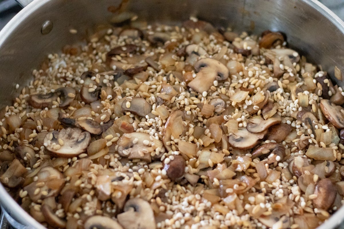 Sauteing onion and mushrooms, with the rinsed barley added to the pan.