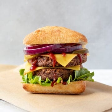 tempeh burger with toppings on a bun sitting on parchment paper.