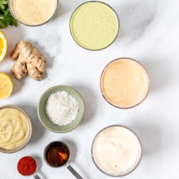 different tahini dressing variations with ingredients on marble background.