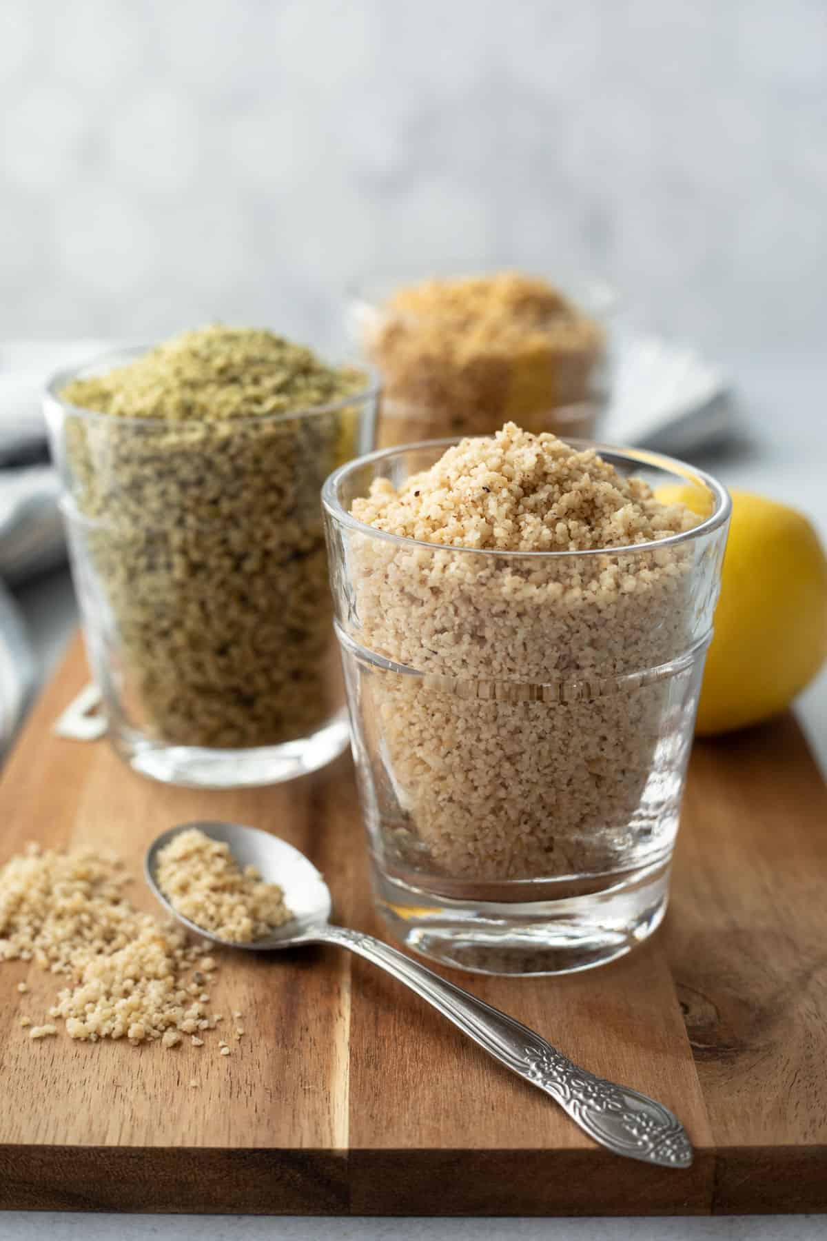 three varieties of homemade vegan parmesan in glasses to show color and texture.