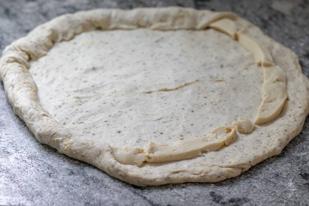 How to make stuffed crust - the dough is rolled out and strips of vegan mozzarella placed about one inch from edges of dough.