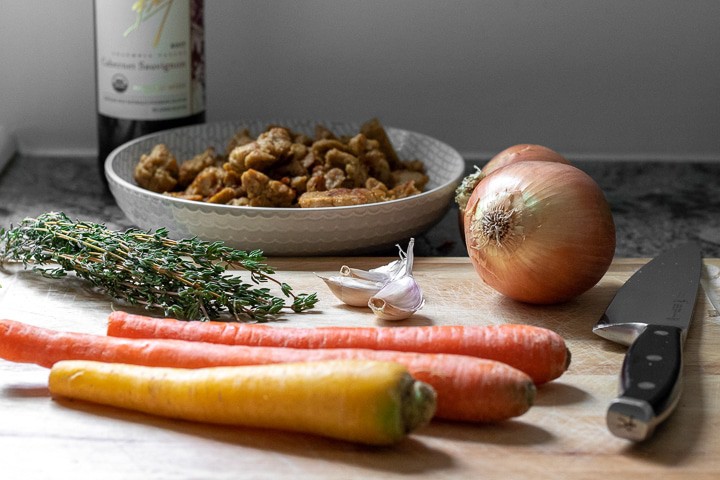 carrots, onion, garlic and thyme on a cutting board.