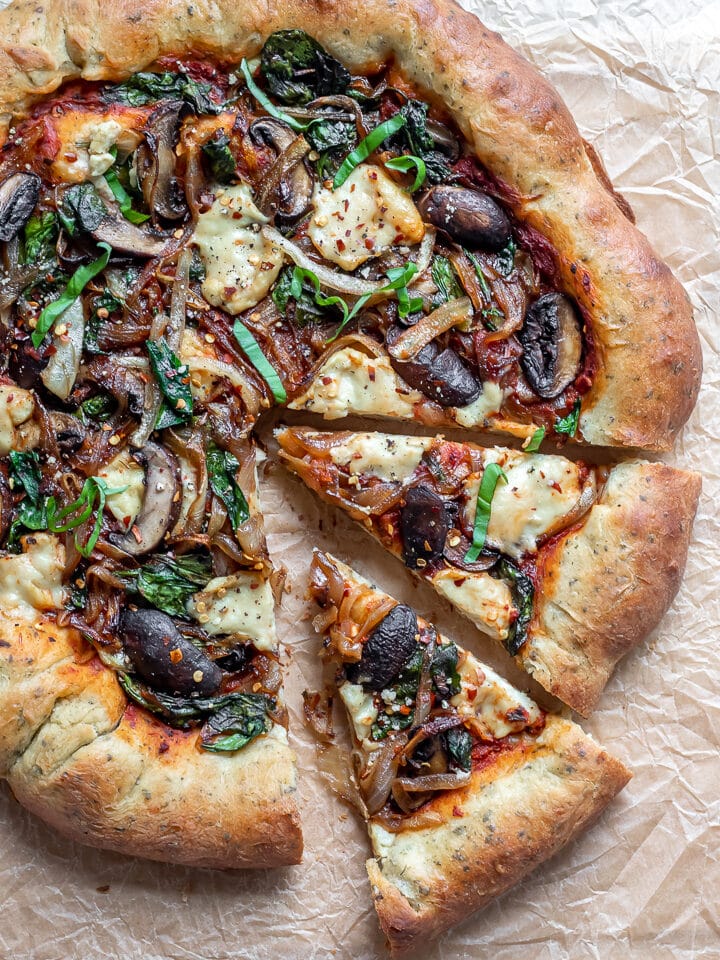 Vegan stuffed crust pizza topped with warm, melted cheese, onions and mushrooms