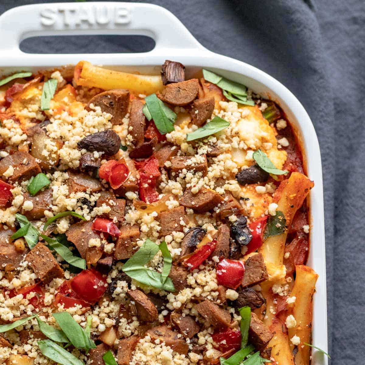 white baking dish filled with baked ziti and sprinkled with vegan parmesan.