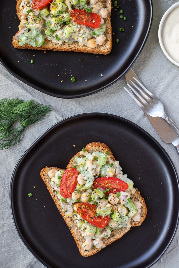 overhead shot of chickpea salad sandwiches on black plates