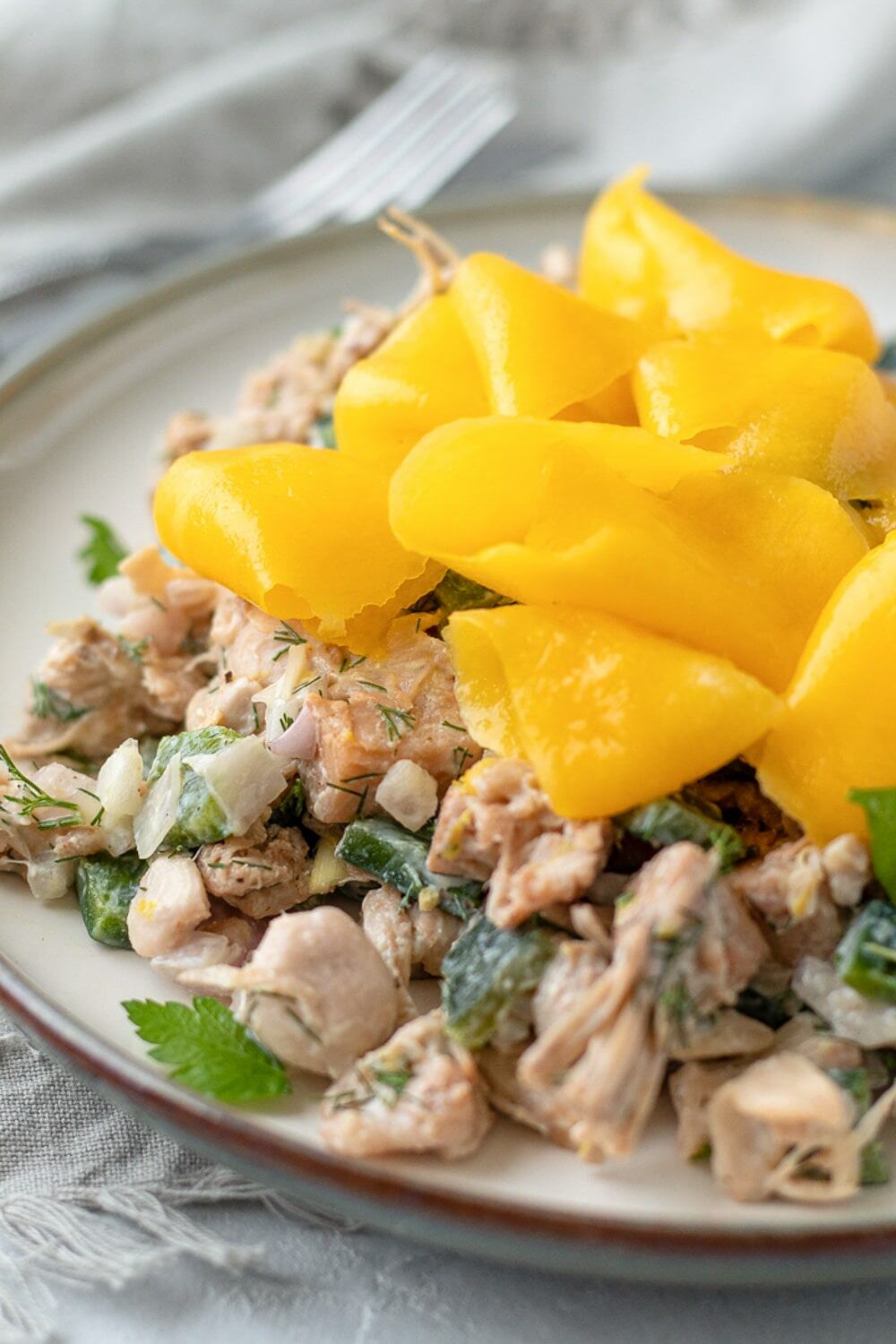 close up of jackfruit salad with fresh herbs and mango ribbons arranged on top.