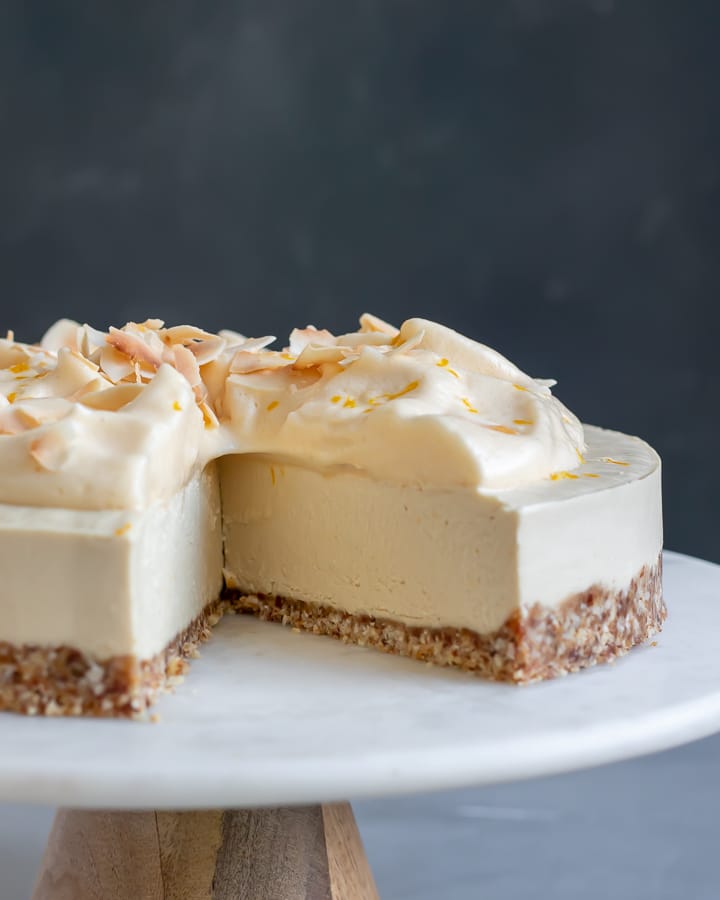 Meyer Lemon Vegan Cheesecake on marble and wood cake stand.