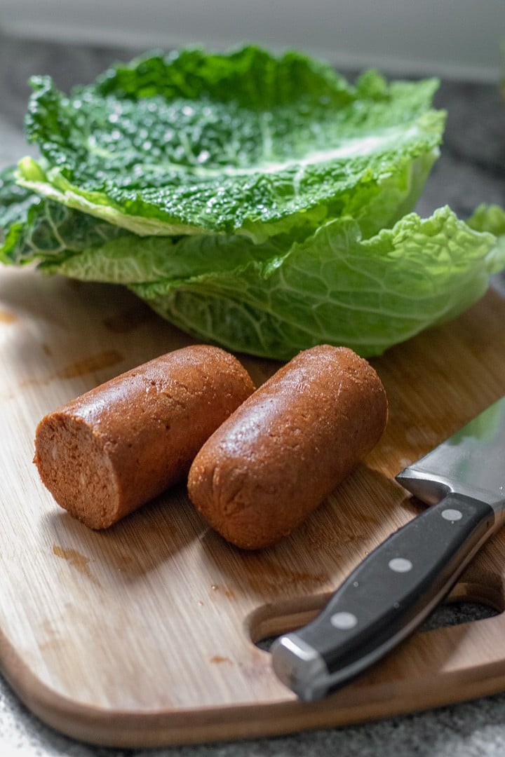 vegan chorizo and cabbage leaves on cutting board.