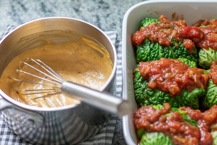 Cabbage rolls topped with salsa plus vegan cheese in a saucepan.