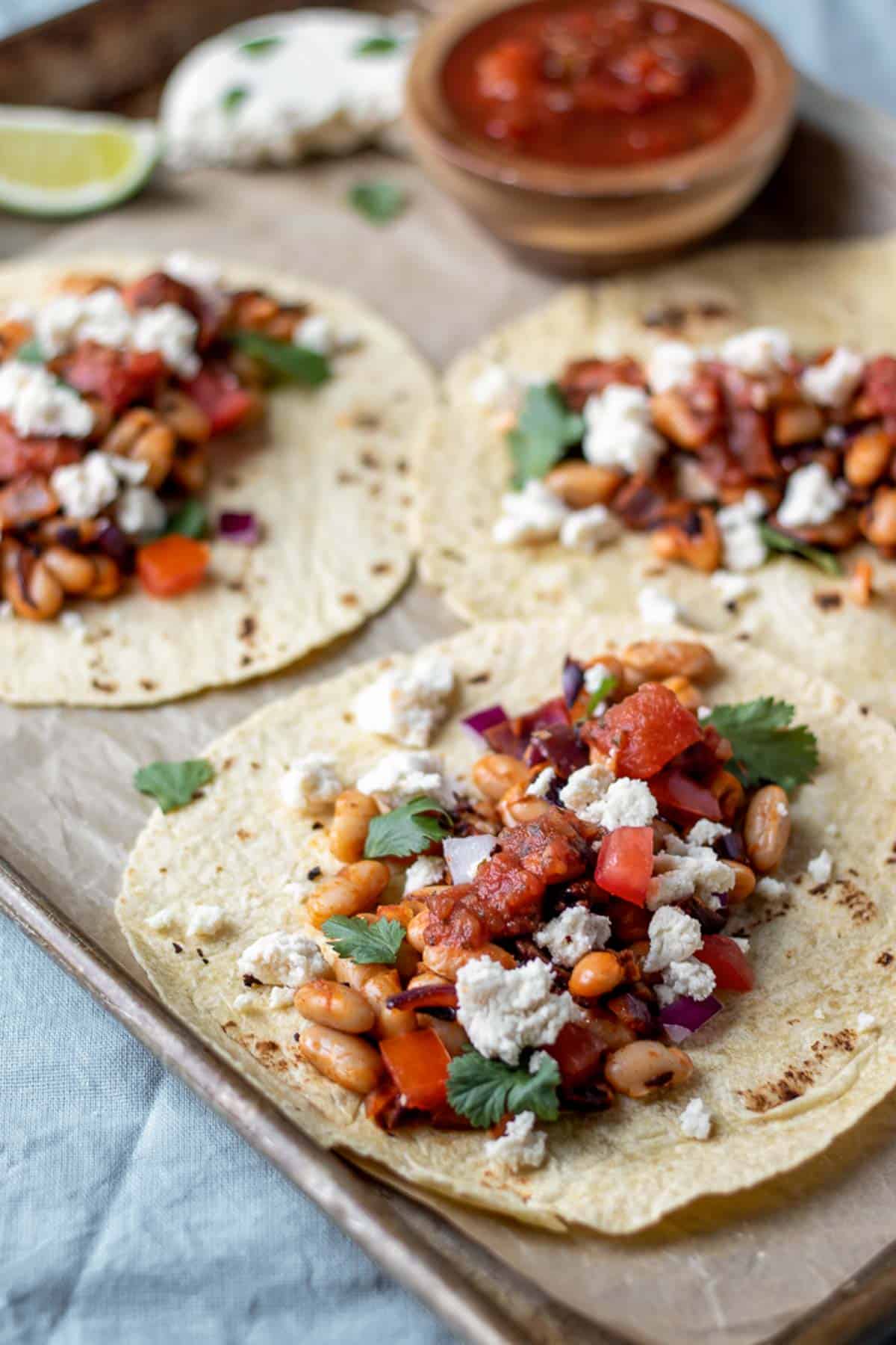 White bean tacos on corn-flour tortillas with cheese and salsa.