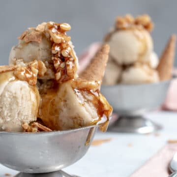 Banana Nice Cream topped with wet walnuts in a small silver bowl