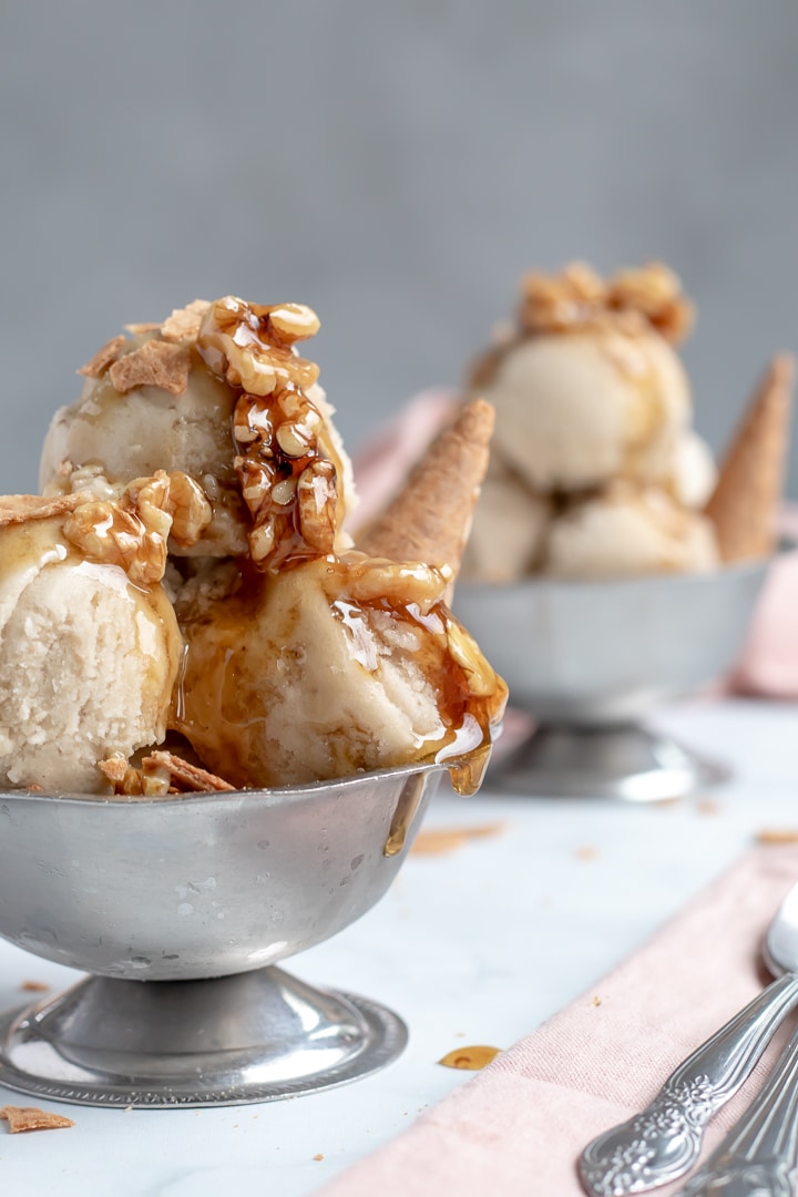 Banana Nice Cream topped with wet walnuts in a small silver bowl