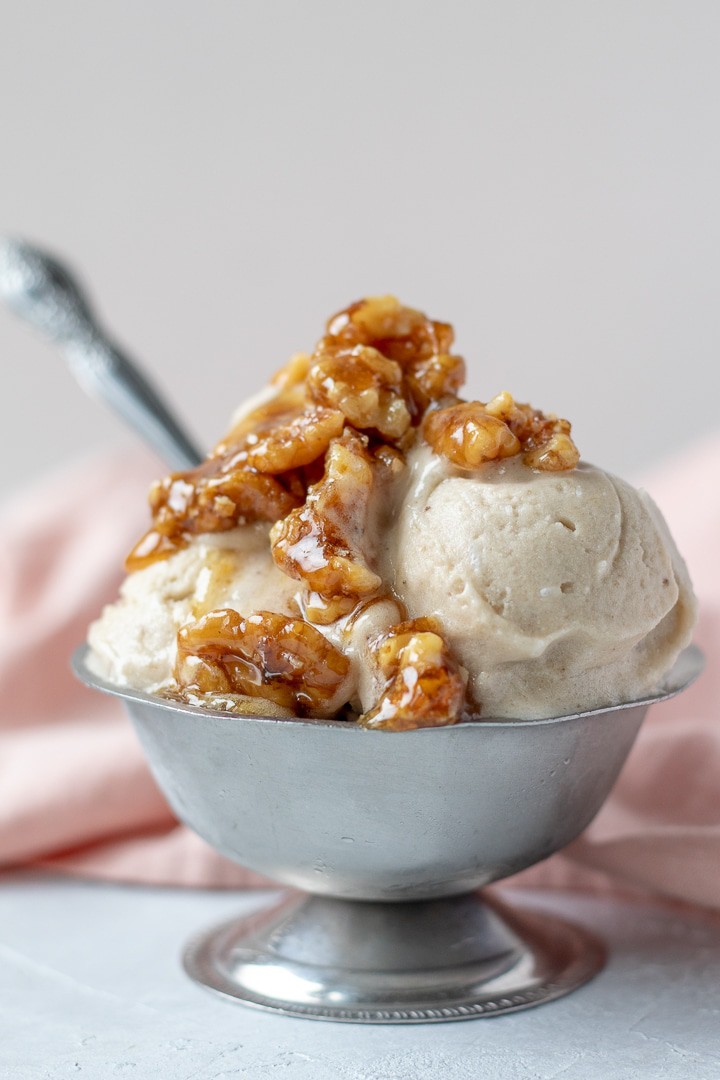 Banana Nice Cream topped with wet walnuts in a small silver bowl