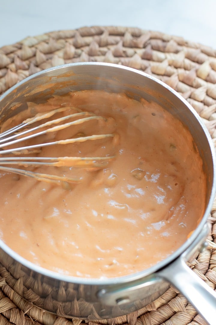 whisking warm vegan queso in a small sauce pan.