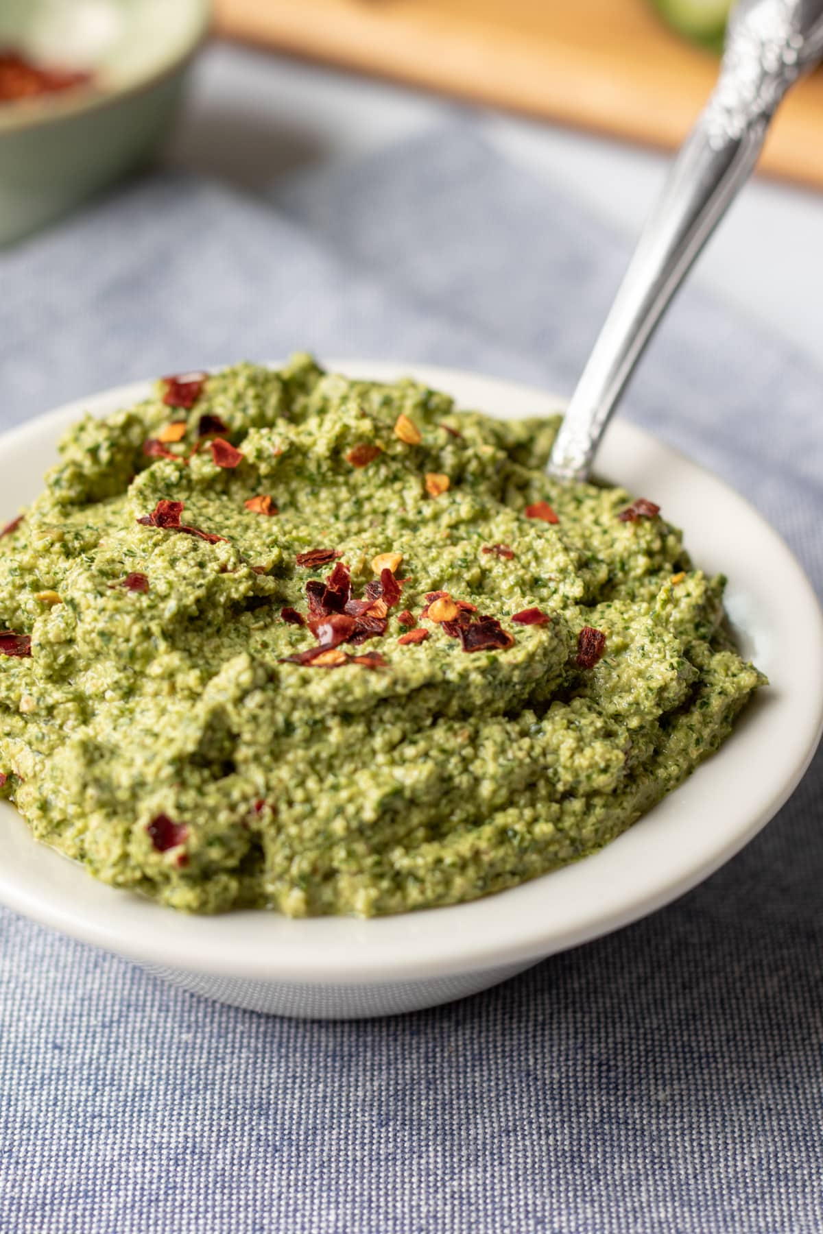 close up of thick green cilantro sauce in a small bowl.