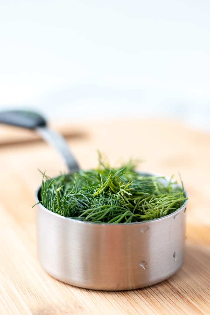 Half cup measuring cup filled with dill
