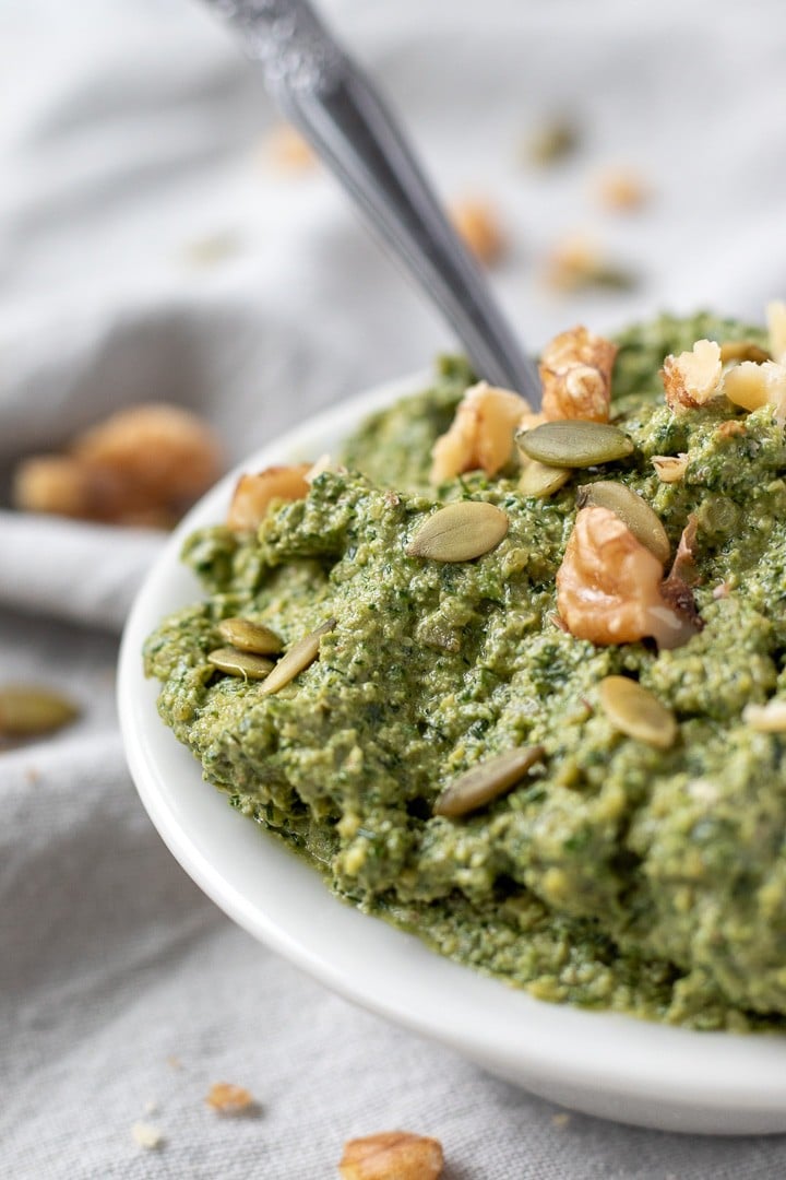 close up of chunky and thick dill pesto in a small white bowl.