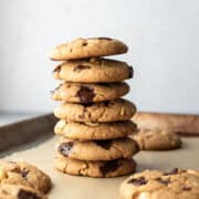 A stack of Spelt Cookies filled with chocolate chips and peanuts on a baking sheet.