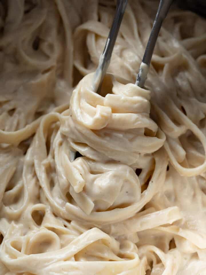 close up of creamy vegan alfredo in a pasta pot.