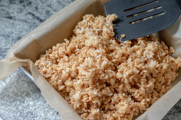 Pressing mixture into a parchment-lined square pan.