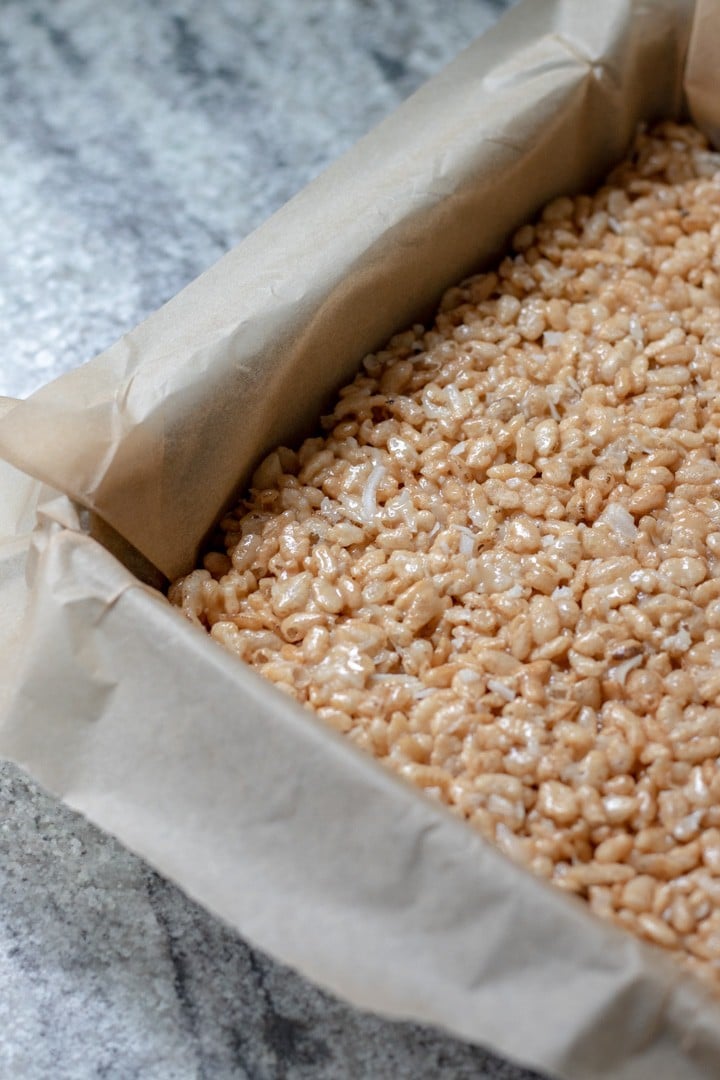 pressing rice krispie treat mixture into an 8x8 pan