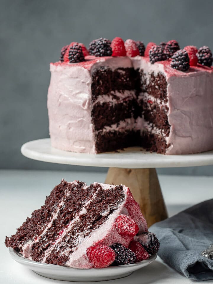Vegan Chocolate Layer Cake on a cake stand and a slice on a plate