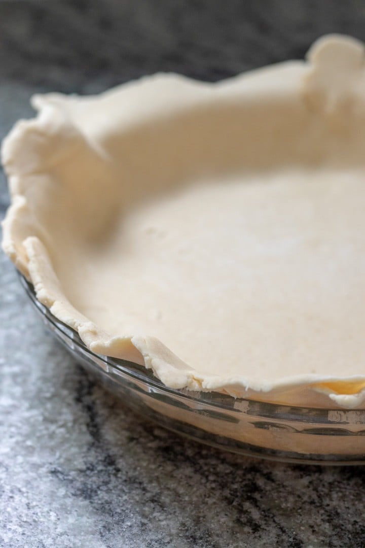 rolled pie dough draped over pie plate.