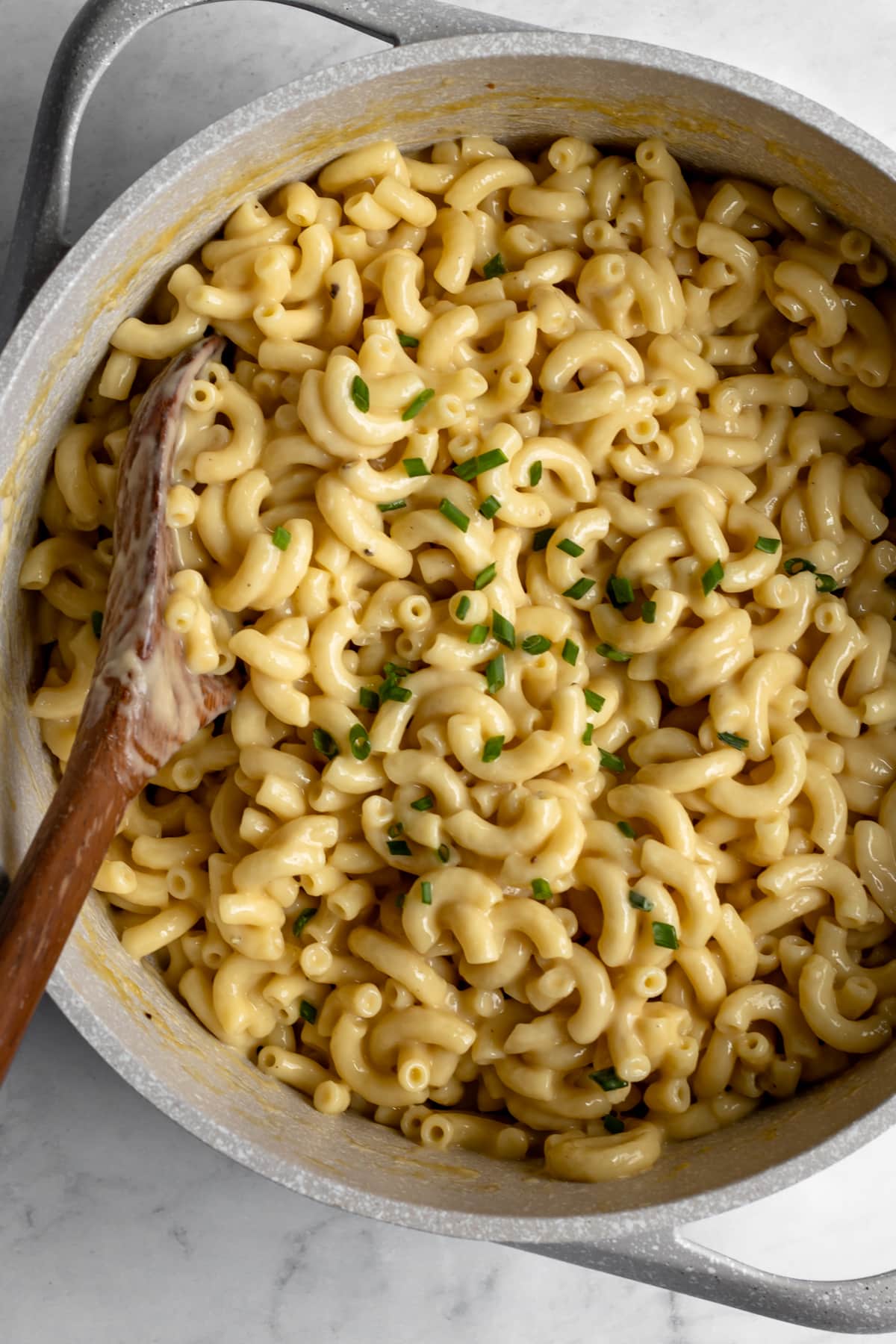 overhead shot of a pot full of vegan macaroni garnished with chives.