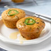 two jalapeno cornbread muffins on a small white plate.