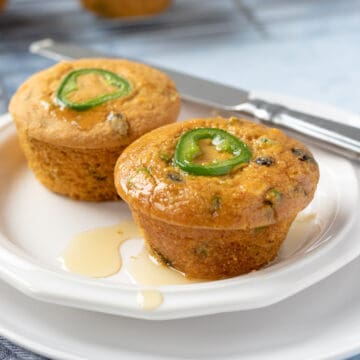 two jalapeno cornbread muffins on a small white plate.