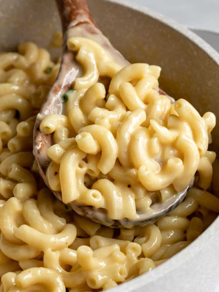 close up of creamy vegan mac and cheese on a wooden spoon.