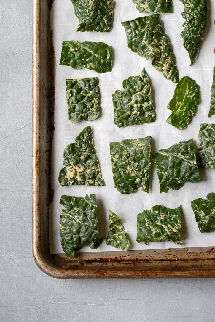 kale chips on a baking sheet ready to be go in the oven.
