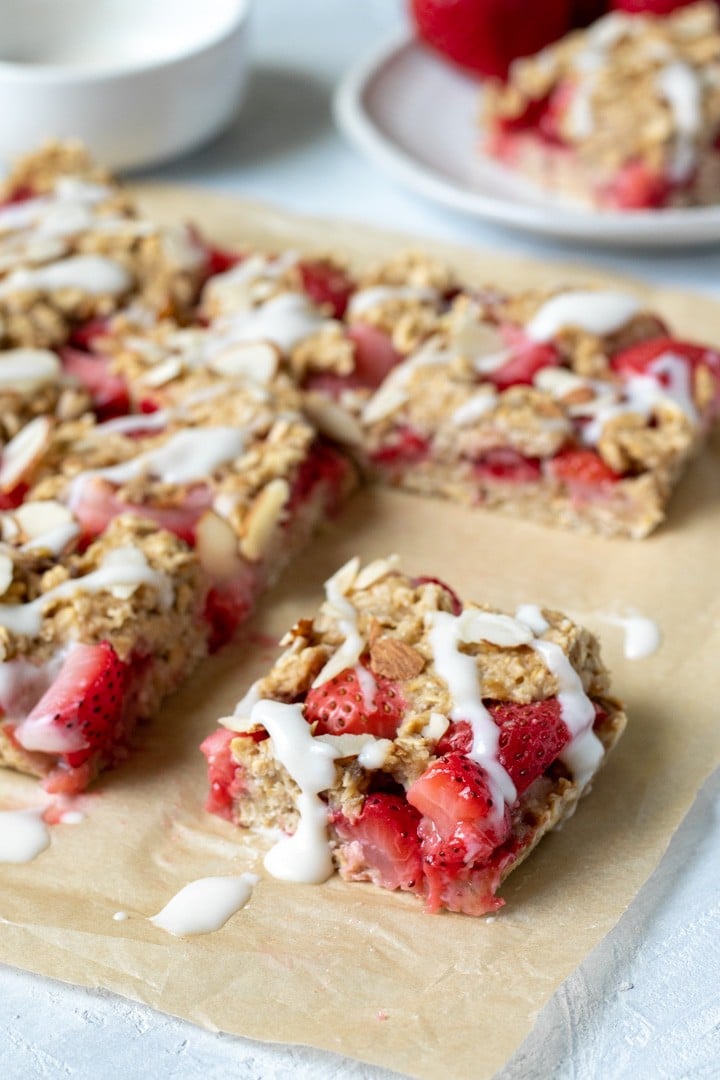 Strawberry Breakfast Bars on parchment, drizzled with coconut butter glaze