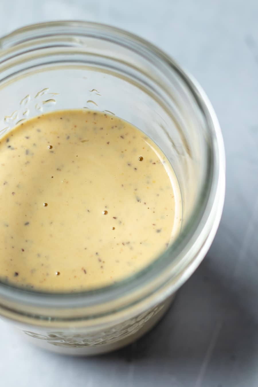 golden-colored Vegan Caesar Dressing in a glass jar.